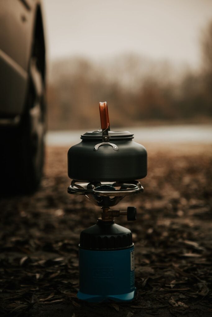 Een ketel op een kleine gasbrander tussen de bladeren