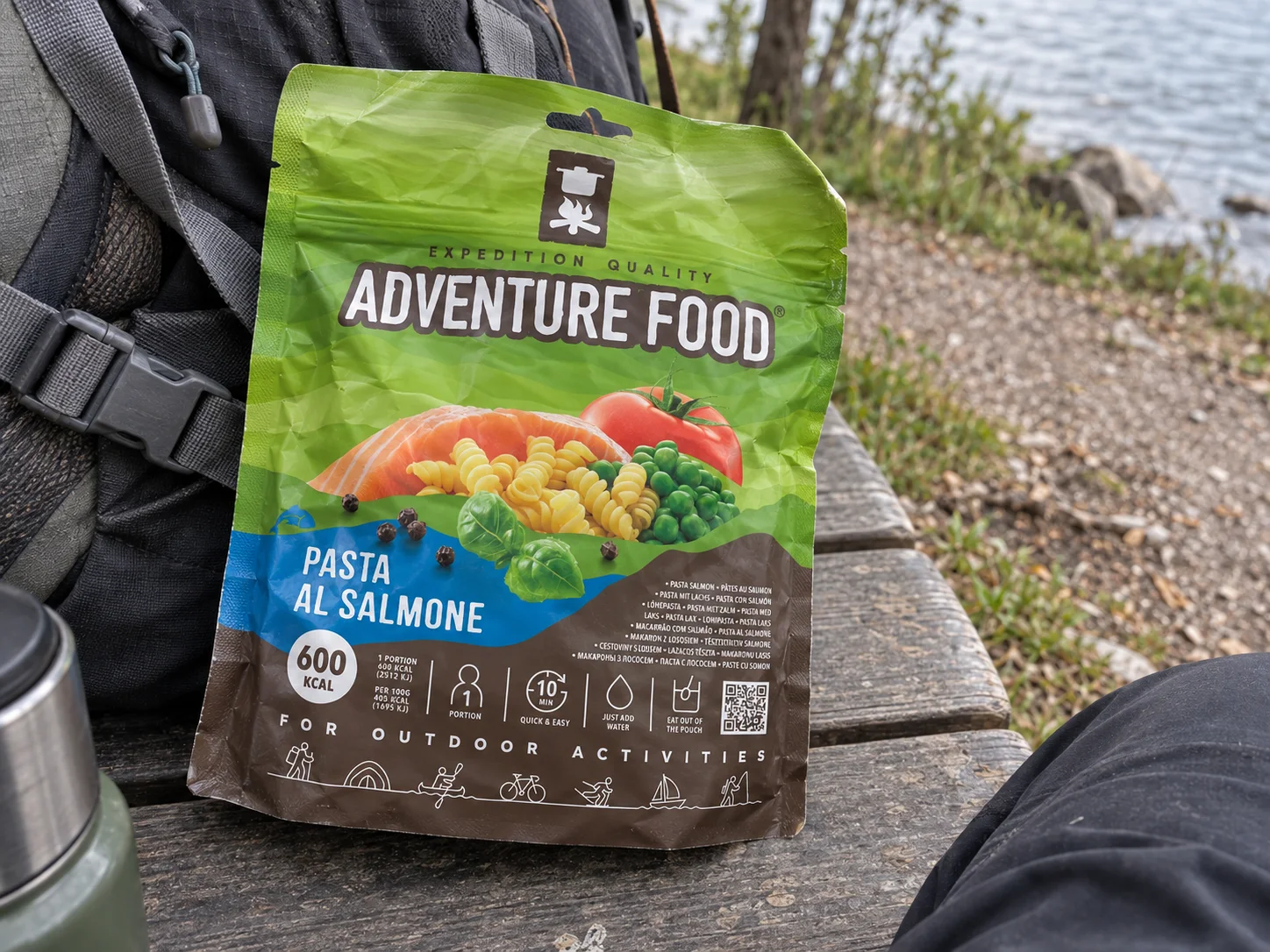 Adventure Food Pasta al Salmone in de verpakking tijdens een pauze onderweg, naast wandeluitrusting.