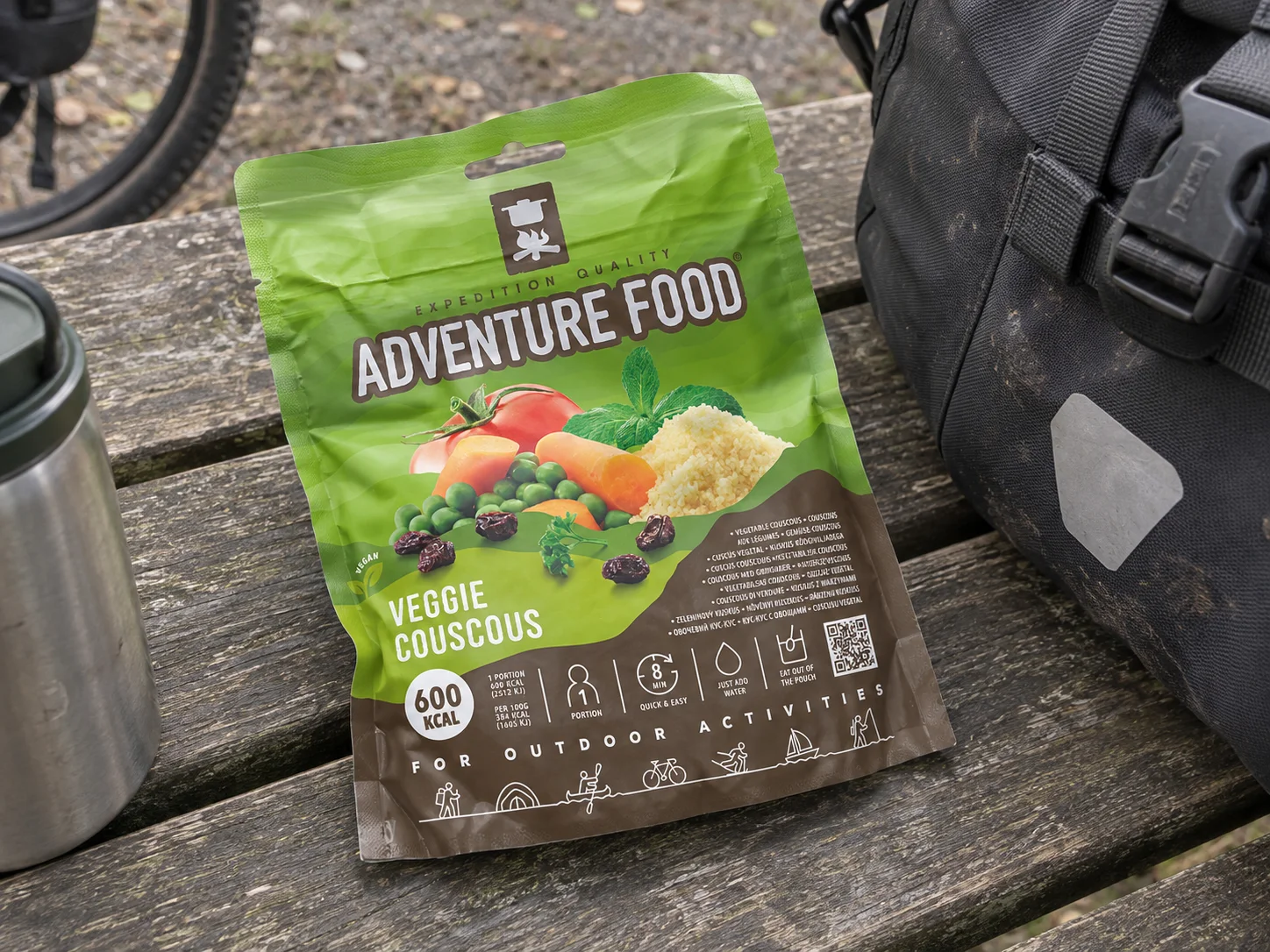 Adventure Food Veggie Couscous in de verpakking tijdens een pauze onderweg, naast wandeluitrusting.