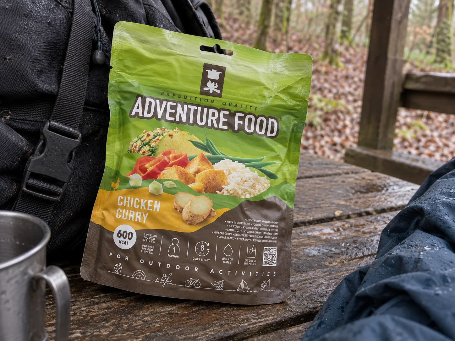 Adventure Food Chicken Curry in de verpakking tijdens een pauze onderweg, naast wandeluitrusting.