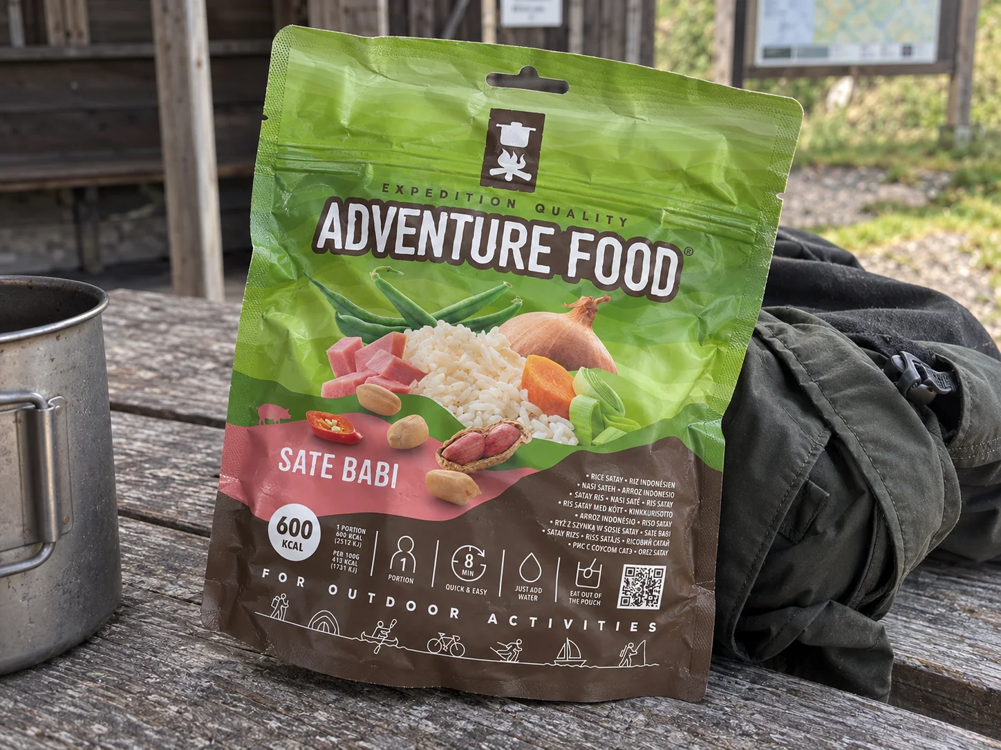 Adventure Food Sate Babi in de verpakking tijdens een pauze onderweg, naast wandeluitrusting.