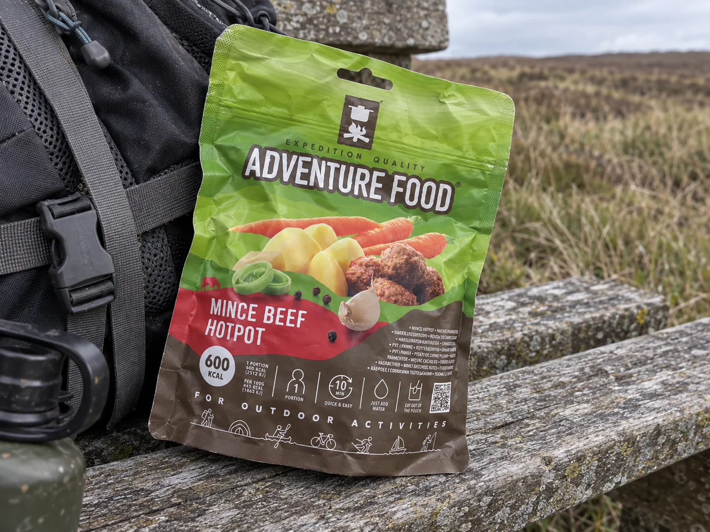 Adventure Food Mince Beef Hotpot in de verpakking tijdens een pauze onderweg, naast wandeluitrusting.