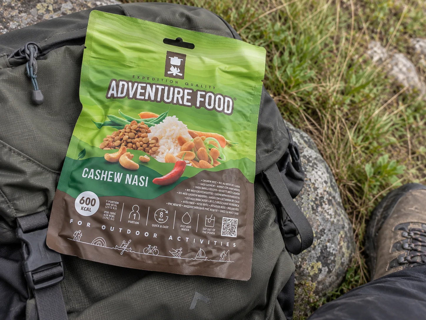 Adventure Food Cashew Nasi in de verpakking tijdens een pauze onderweg, naast wandeluitrusting.