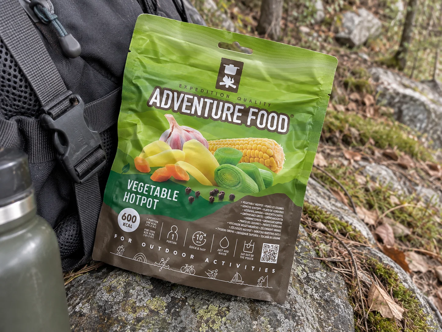 Adventure Food Vegetable Hotpot in de verpakking tijdens een pauze onderweg, naast wandeluitrusting.