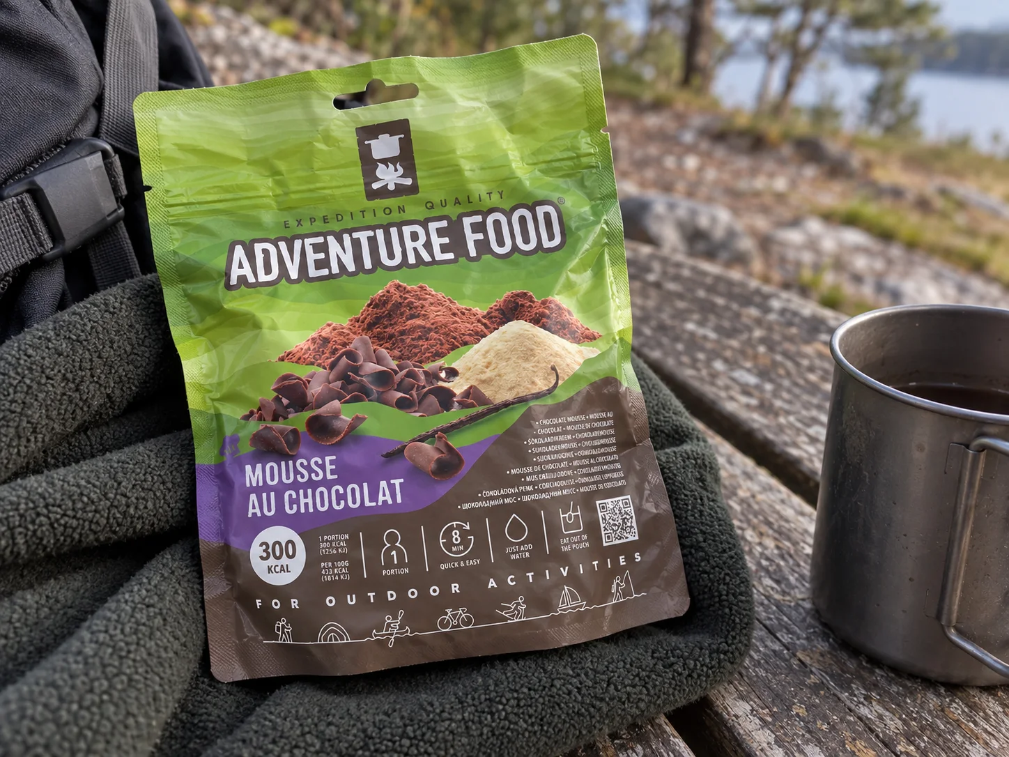 Adventure Food Mousse Au Chocolat in de verpakking tijdens een pauze onderweg, naast wandeluitrusting.