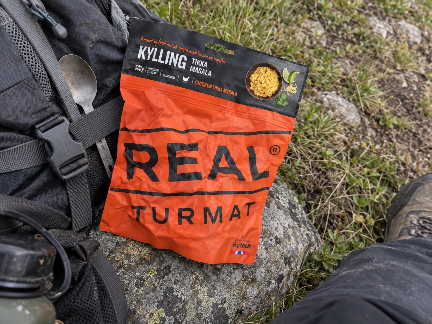 Gekreukte Real Turmat Chicken Tikka Masala-verpakking tijdens een wandelpauze.