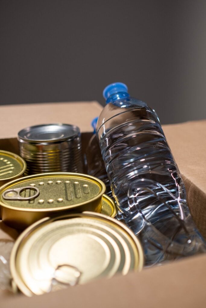 Blikken en een fles water als voorraad op tafel