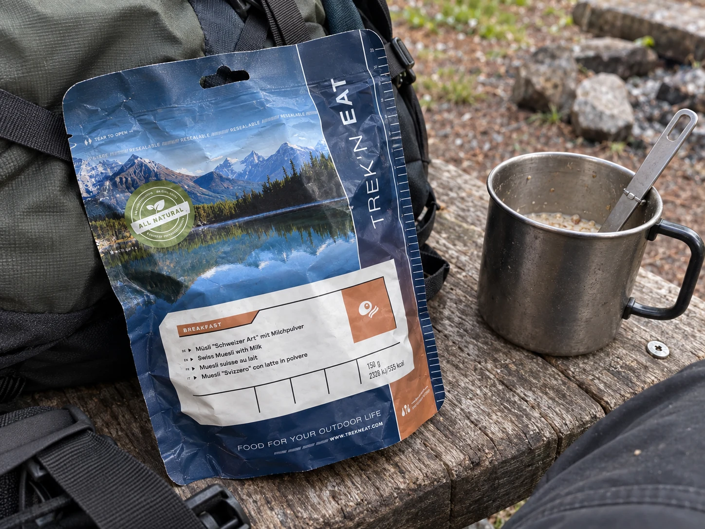 Trek n Eat Swiss Muesli with Milk naast een campingmok en rugzak.